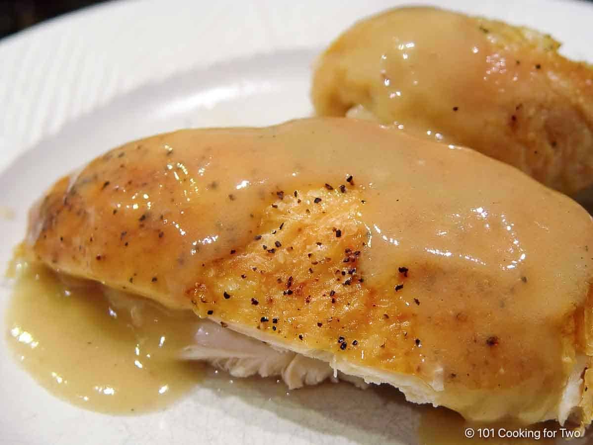 Chicken with gravy on a white plate.