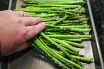Coating asparagus with oil and garlic.