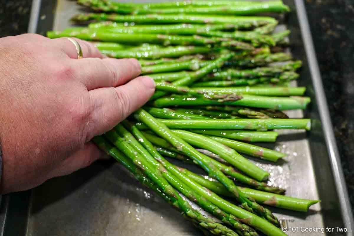 Coating asparagus with oil and garlic.