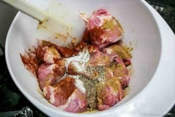Coating pork with seasoning in a bowl.