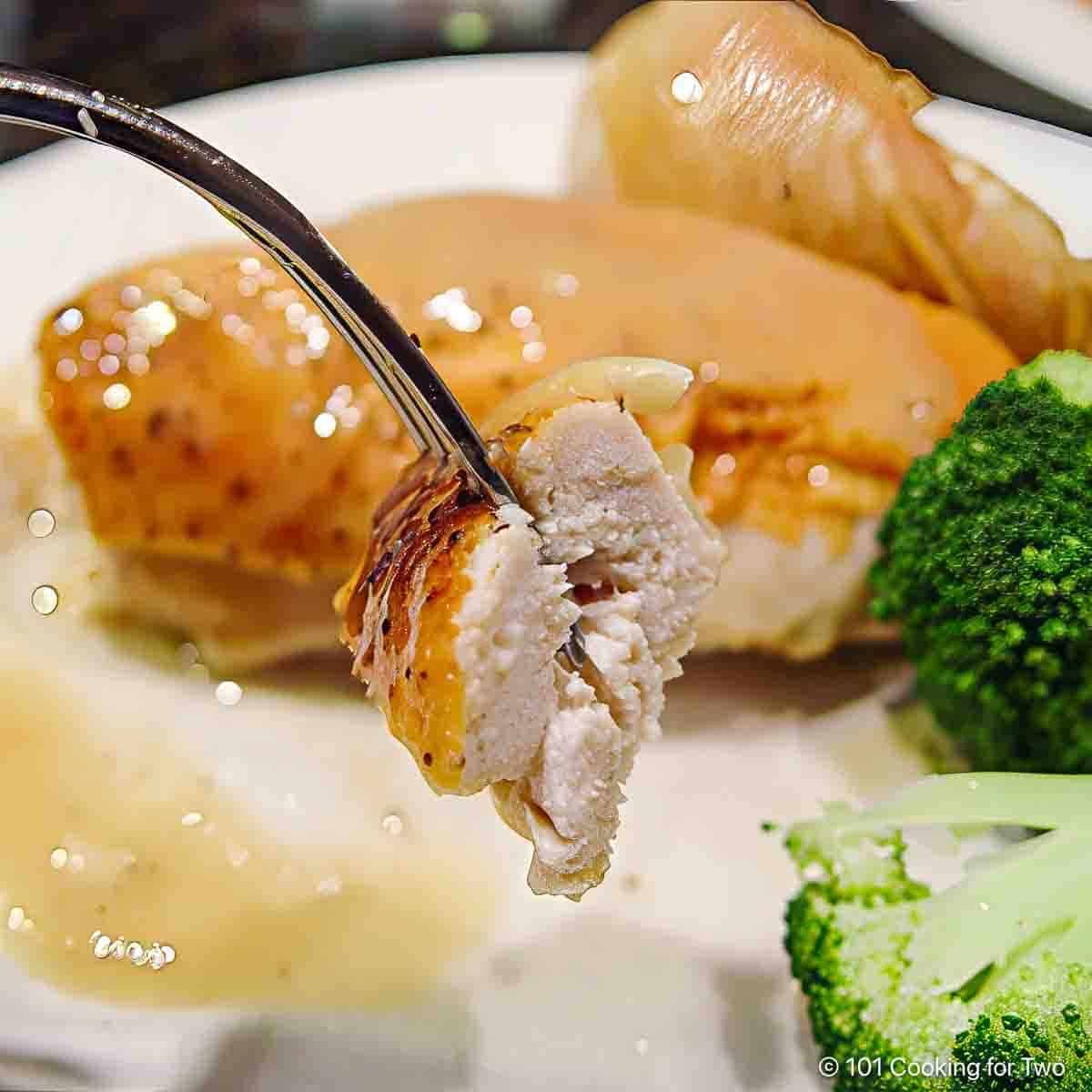 A piece of roasted chicken on a fork.