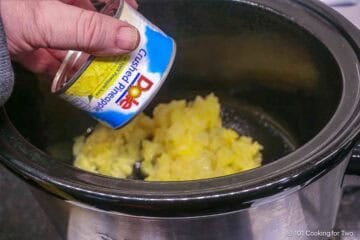 Pour crushed pineapple into the crock pot.