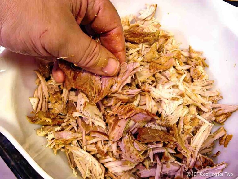 Shredding pork loin by hand in a bowl.