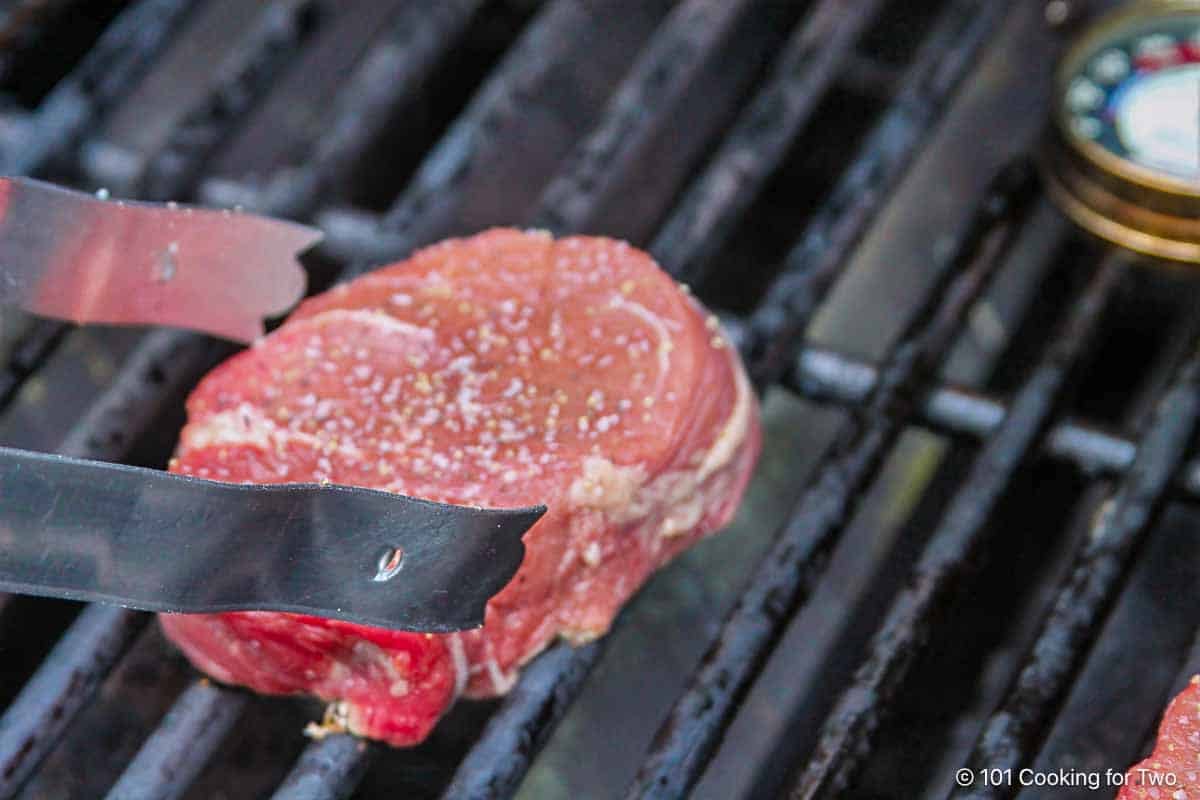 Filet mignon searing on a hot gas grill.