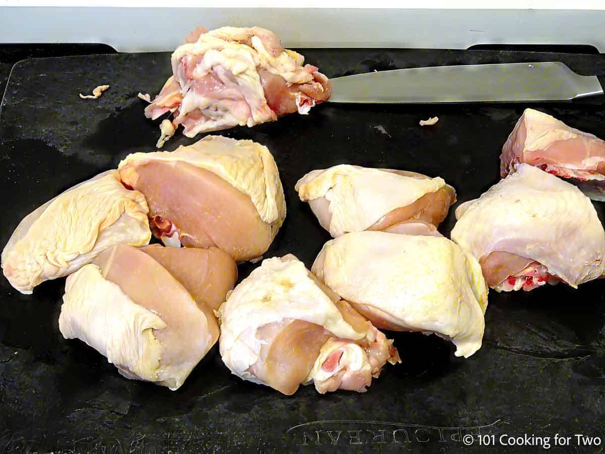 Cutting split chicken breasts into pieces.