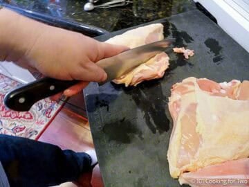 Cuttting ribs off split chicken breasts.