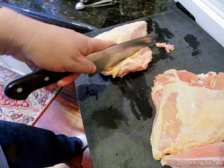 Cuttting ribs off split chicken breasts.