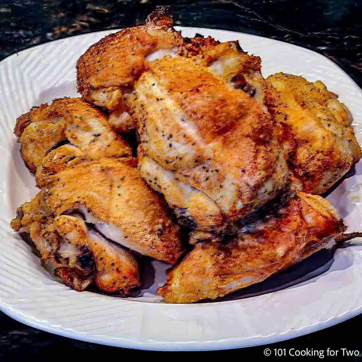 Pile of cooked bone-in chicken breasts.