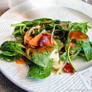 Spinach salad with bacon and dressing.