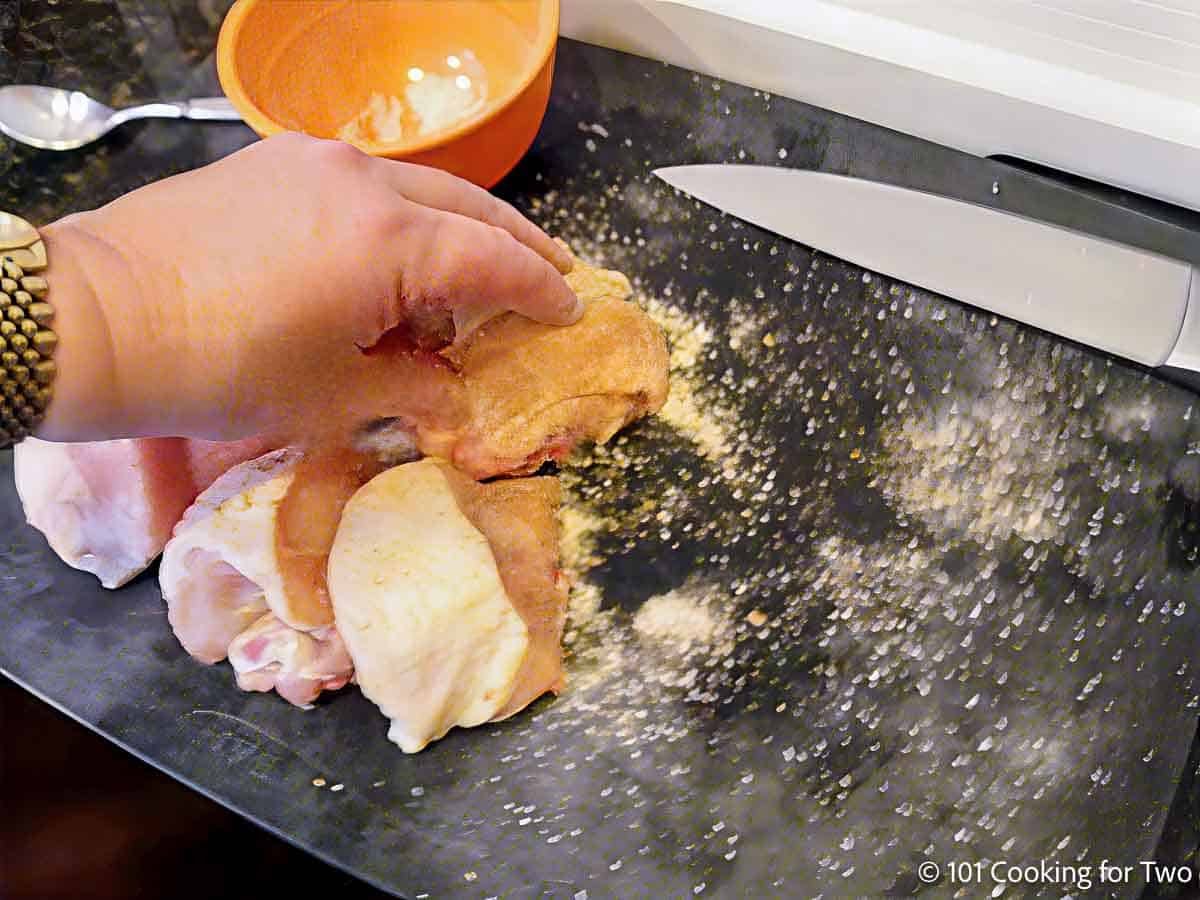 Seasoning the chicken by hand.