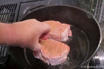 Placing a thick cut pork chop in a pan to sear.