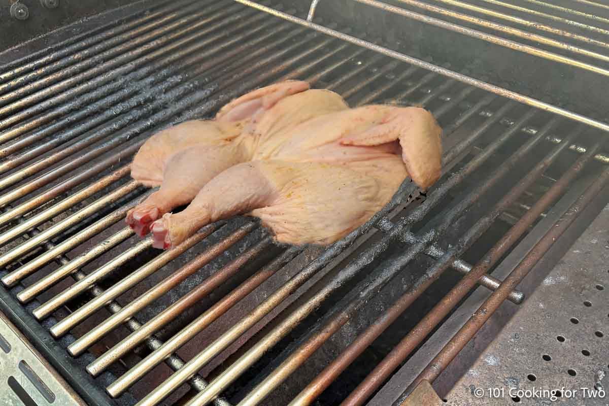 Raw flattend chicken on a grill.