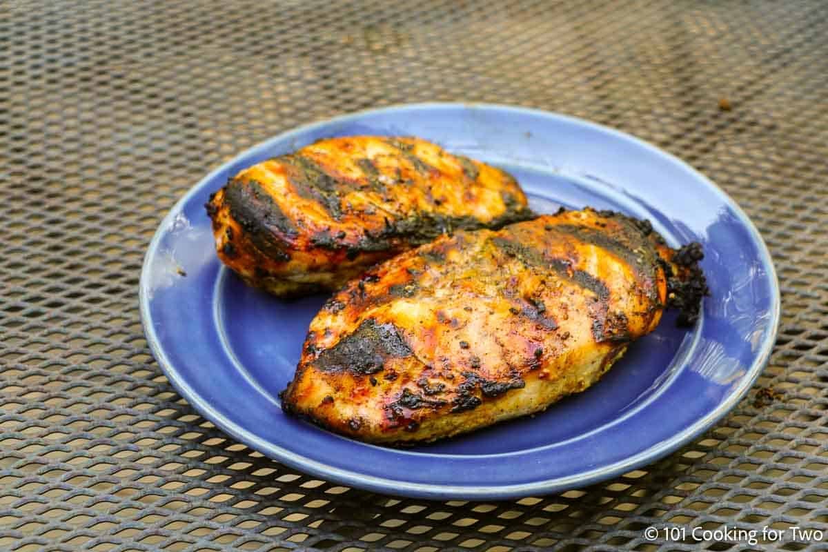 Two chicken breasts grill on a blue plate.