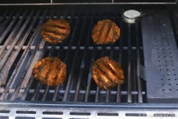 Four ground chicken burgers on a grill.