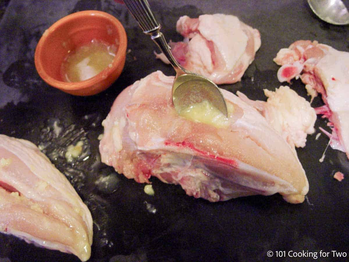 Adding garlic butter into the pocked in a split chicken breast.