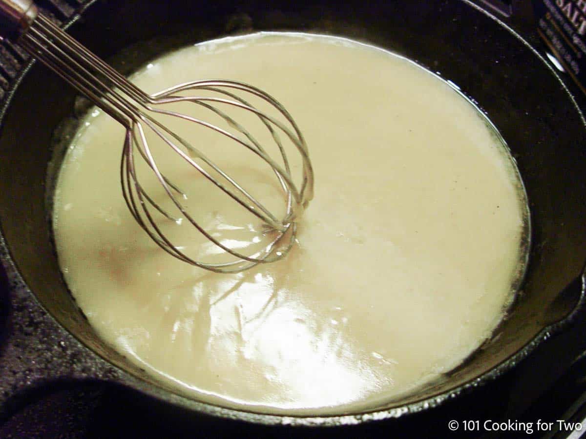 Whisking gravy in a cast iron pan.